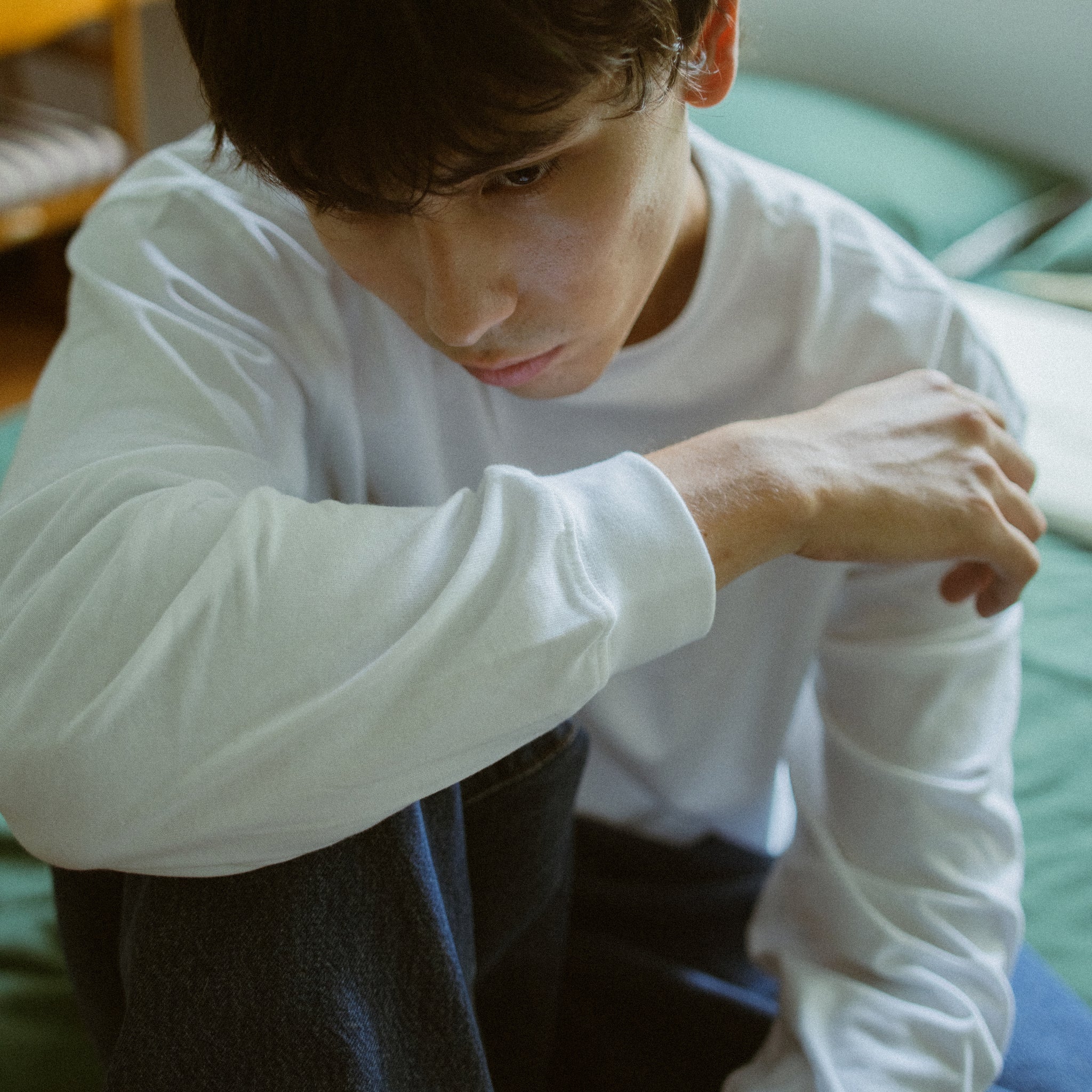 Person wearing a white long-sleeve shirt sitting on a couch.