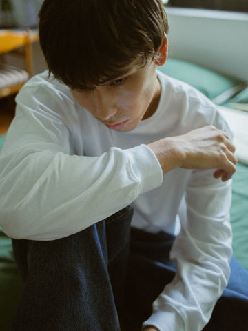 Person wearing a white long-sleeve shirt sitting on a couch.